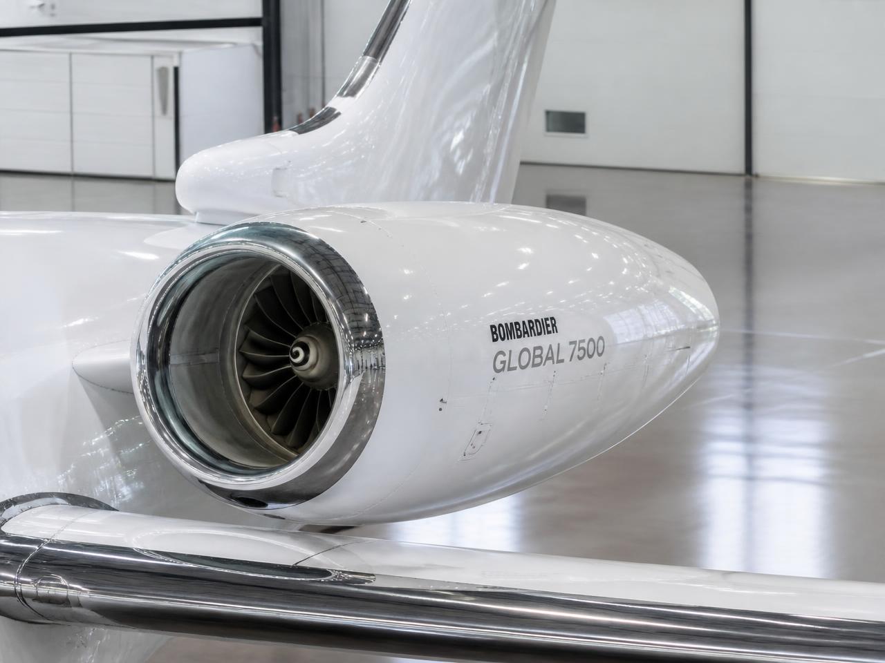 Mirror-polished white Bombardier engine nacelle and winglet in a bright hangar